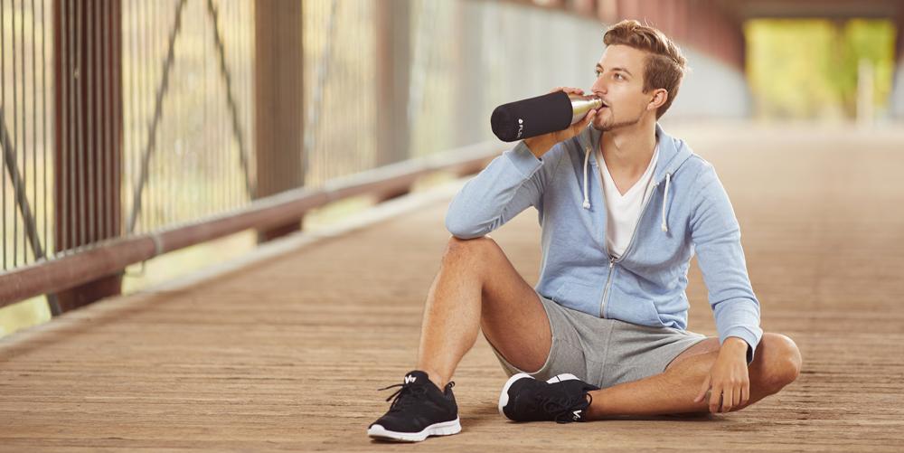 Mann beim Trinken aus der FLSK Flasche