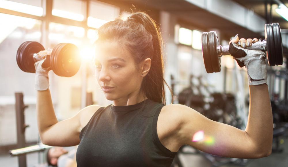 Frau im Fitnesstudio beim Gewichte heben